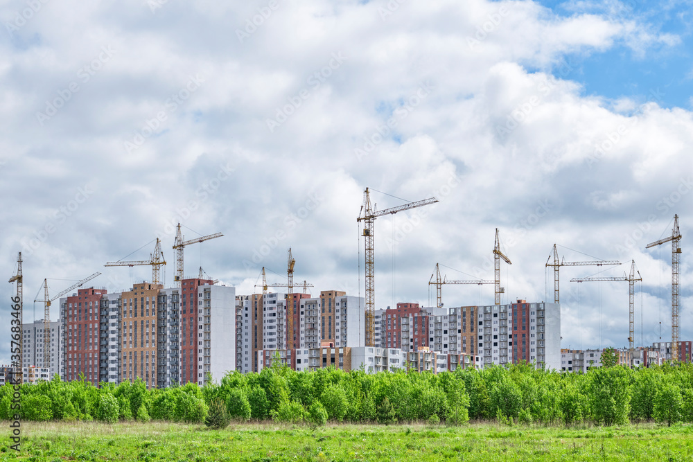 A large construction site, including several tower cranes working on the construction complex, surrounded by forest. A large construction site, including several tower cranes working on the construction complex, surrounded by forest.