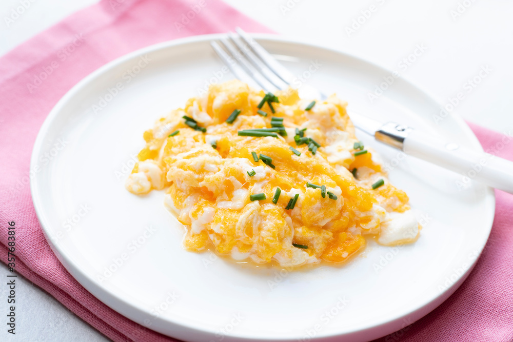 Scrambled eggs on a white plate. Healthy food or breakfast concept.