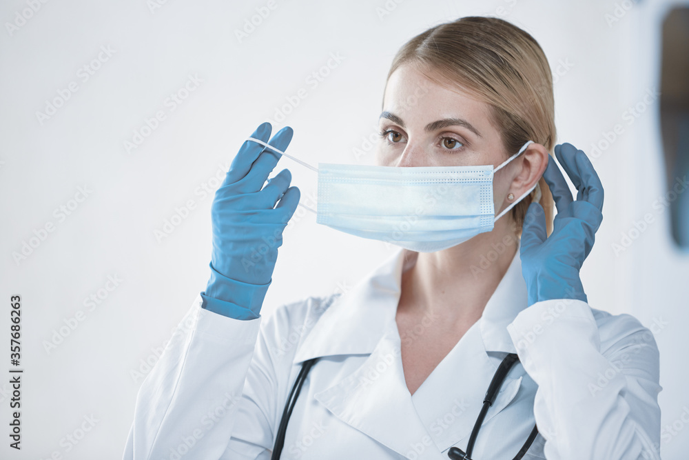 A young doctor girl puts on a protective face mask before work. The concept of health