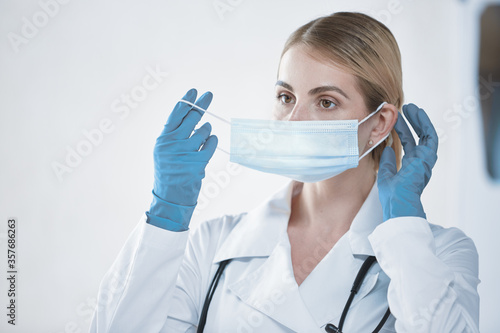 A young doctor girl puts on a protective face mask before work. The concept of health