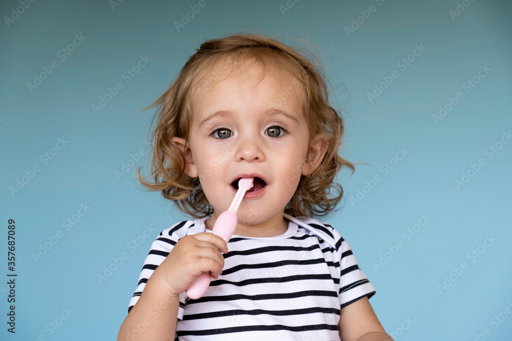 Little girl brushing her teeth on blue background. Little girl brushing her teeth on blue background.