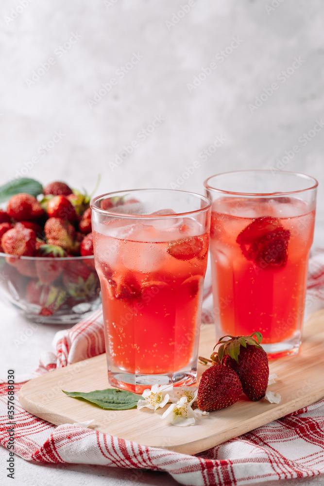 A refreshing summer drink made from strawberries, juice, soda with ice cubes and slices of berries, in a beautiful glass with water droplets, still life of cocktails on a wooden board, red napkin A refreshing summer drink made from strawberries, juice, soda with ice cubes and slices of berries, in a beautiful glass with water droplets, still life of cocktails on a wooden board, red napkin