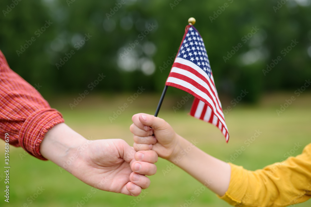 Fototapeta premium Young woman and little child holding american flag on grey background. Independence Day concept. National holiday.