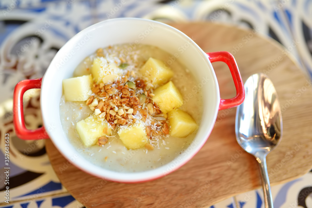 Pudding with fruits, nuts and seeds in red bowl on the table of cafe. Dessert. Healthy eating. Pudding with fruits, nuts and seeds in red bowl on the table of cafe. Dessert. Healthy eating.