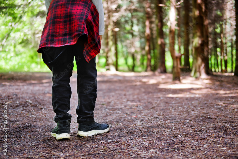 young man walking in the park. Close up view on man's legs in jeans and black leather boots with sunlight against nature blur background. young man walking in the park. Close up view on man's legs in jeans and black leather boots with sunlight against nature blur background.