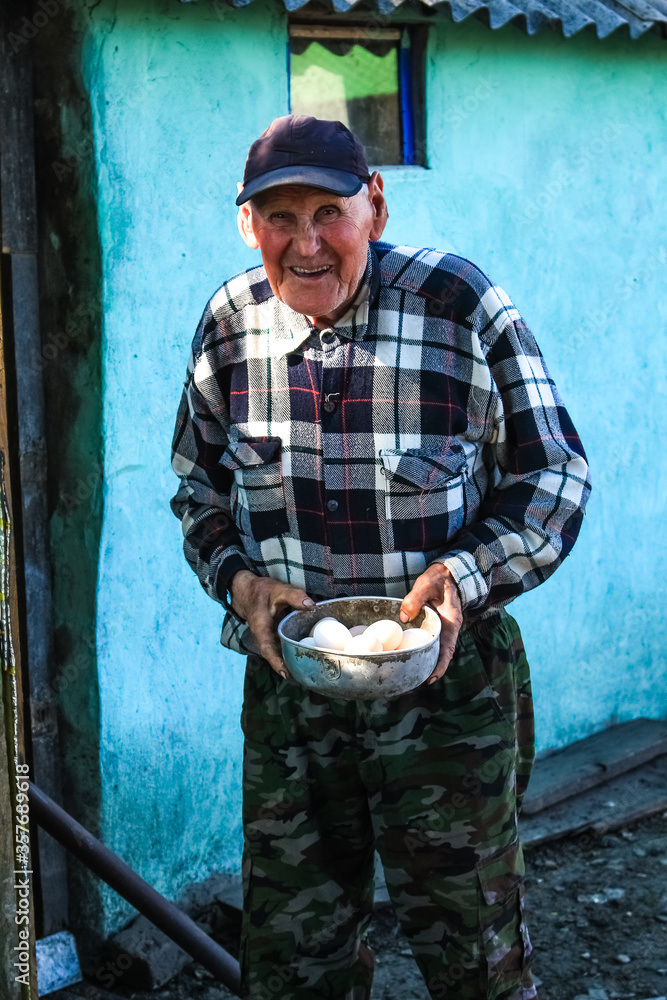 An old grandfather in the village holds chicken eggs in his hands.