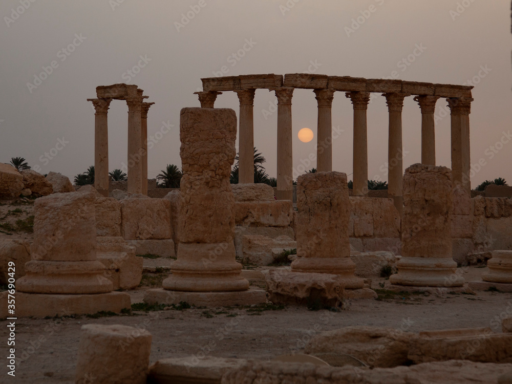 Sun rises between the stone pillars at the ancient city of Palmyra, Syria