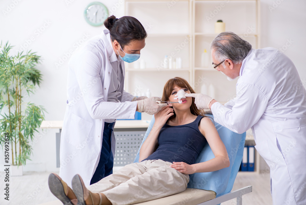 Obraz premium Two male doctors and young woman in plastic surgery concept