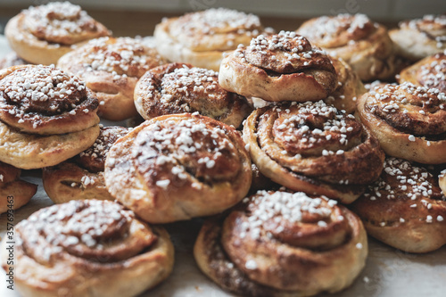 Batch of freshly baked homemade Swedish style cinnamon rolls / buns with pearl sugar. Slightly increased contrast, vintage style photo -Image © DBER