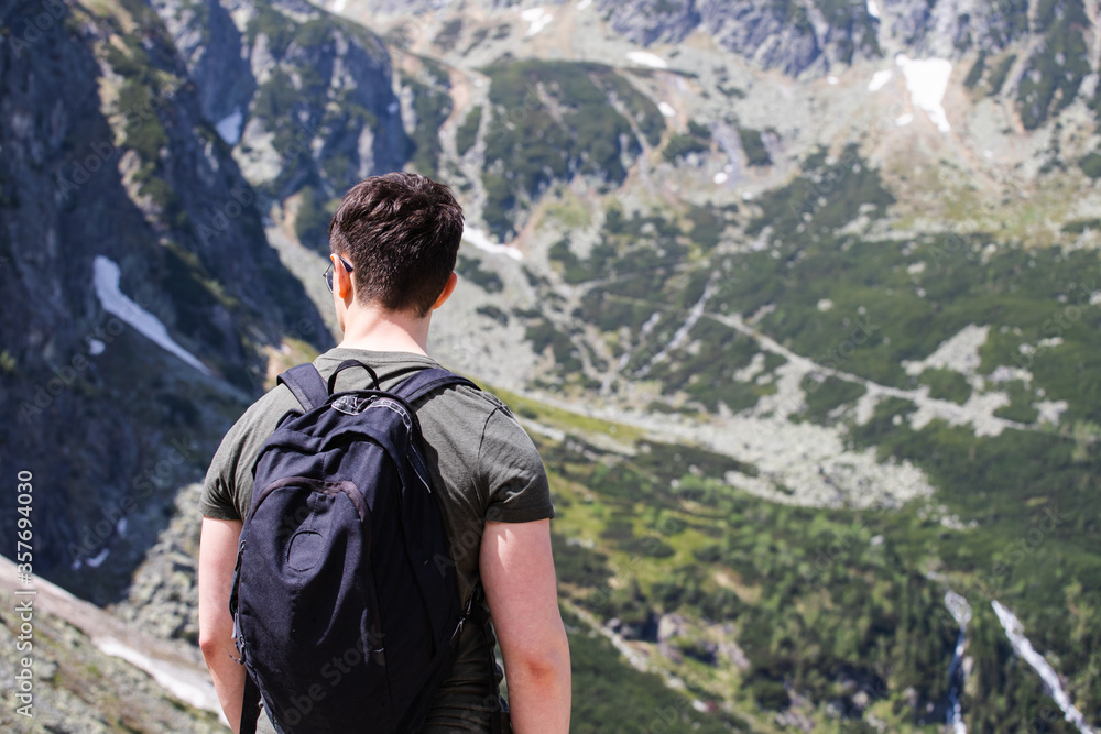 A man looking at the mountain peaks. Hiking traveler with a backpack against the backdrop of the mountains. A man looking at the mountain peaks. Hiking traveler with a backpack against the backdrop of the mountains.