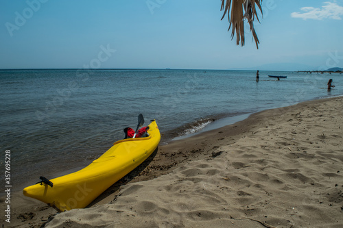 Yellow racing canoe holding still at the shore of a beach in Greece