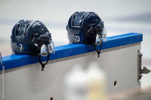 Closeup of two ice hockey helmets standing on the side of a rink. photo