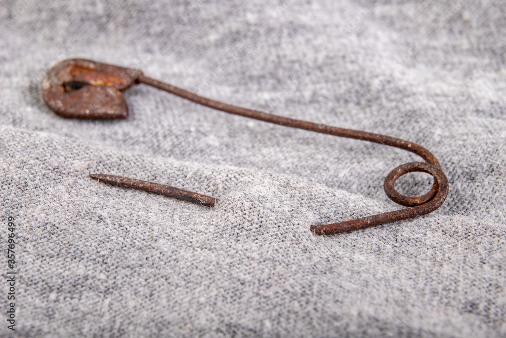 An old rusty safety pin for tailoring works in gray fabric. Accessories  needed for sewing in a sewing room. Stock-Foto | Adobe Stock
