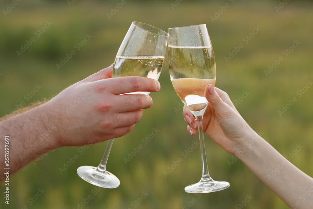 champagne glasses in the hands of a couple on a green background