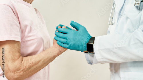 Helping hand. Cropped shot of a doctor in blue sterile gloves holding hands of female senior patient. Healthcare © Svitlana