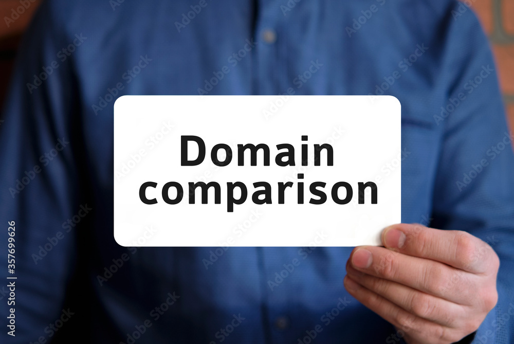 Domain comparison text on a white sign in the hand of a man in a blue shirt Domain comparison text on a white sign in the hand of a man in a blue shirt