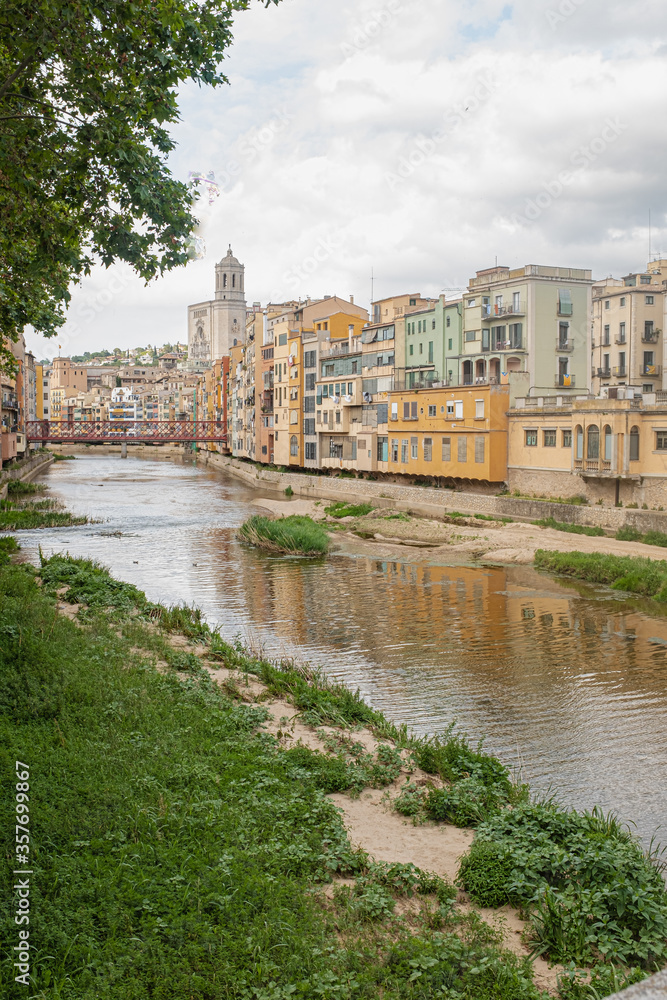 Girona's skyline on a cloudy day with water reflection river houses, bridge and massive cathedral on the horizon