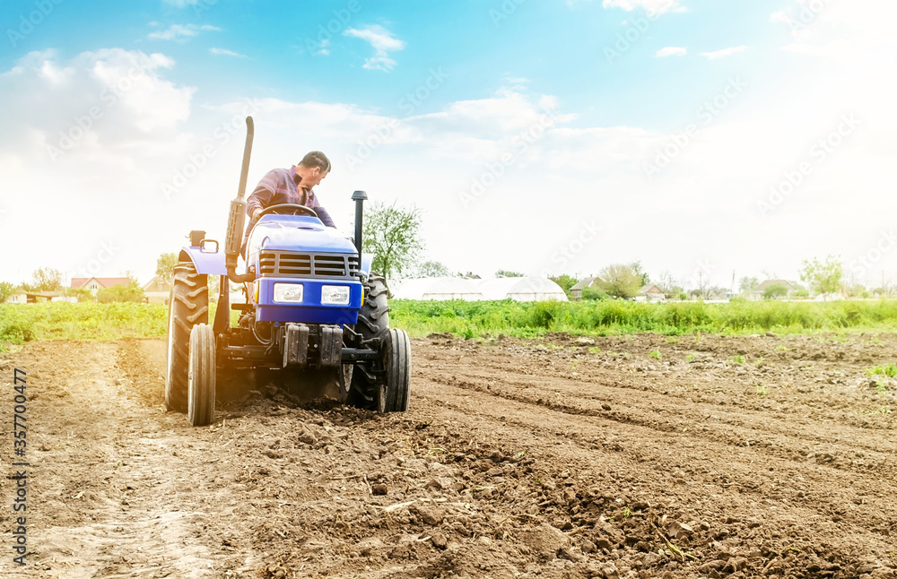Farmer is processing soil on a tractor. Soil milling, crumbling mixing. Loosening surface, cultivating land for further planting. Agriculture, growing organic food vegetables. Agroindustry, farming. - obrazy, fototapety, plakaty 