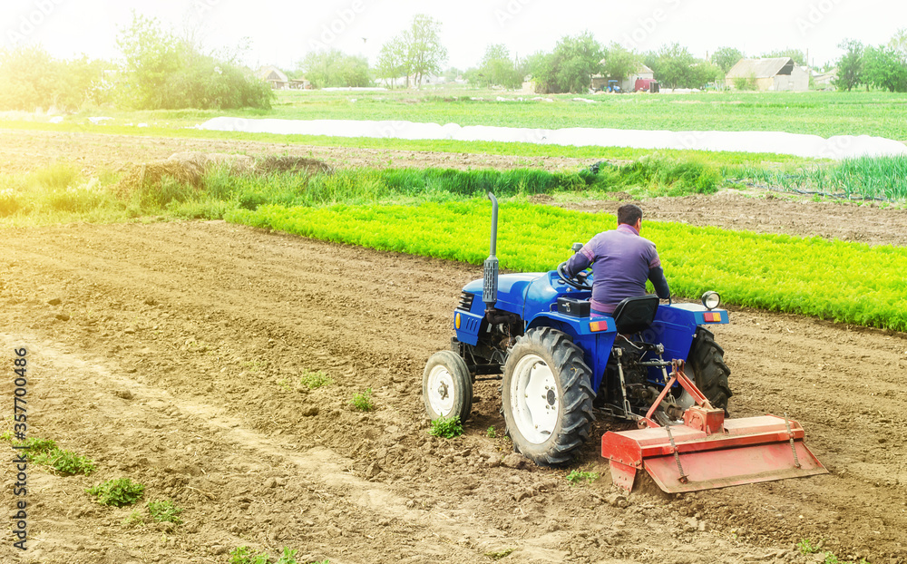 Farmer on a tractor with milling machine loosens, grinds and mixes soil. Loosening the surface, cultivating the land for further planting. Cultivation technology equipment. Farming and agriculture. Farmer on a tractor with milling machine loosens, grinds and mixes soil. Loosening the surface, cultivating the land for further planting. Cultivation technology equipment. Farming and agriculture.