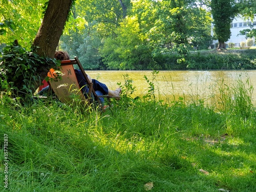 auf dem Rasen am Fluss sitzen ein Picknick machen und der Natur zuhören