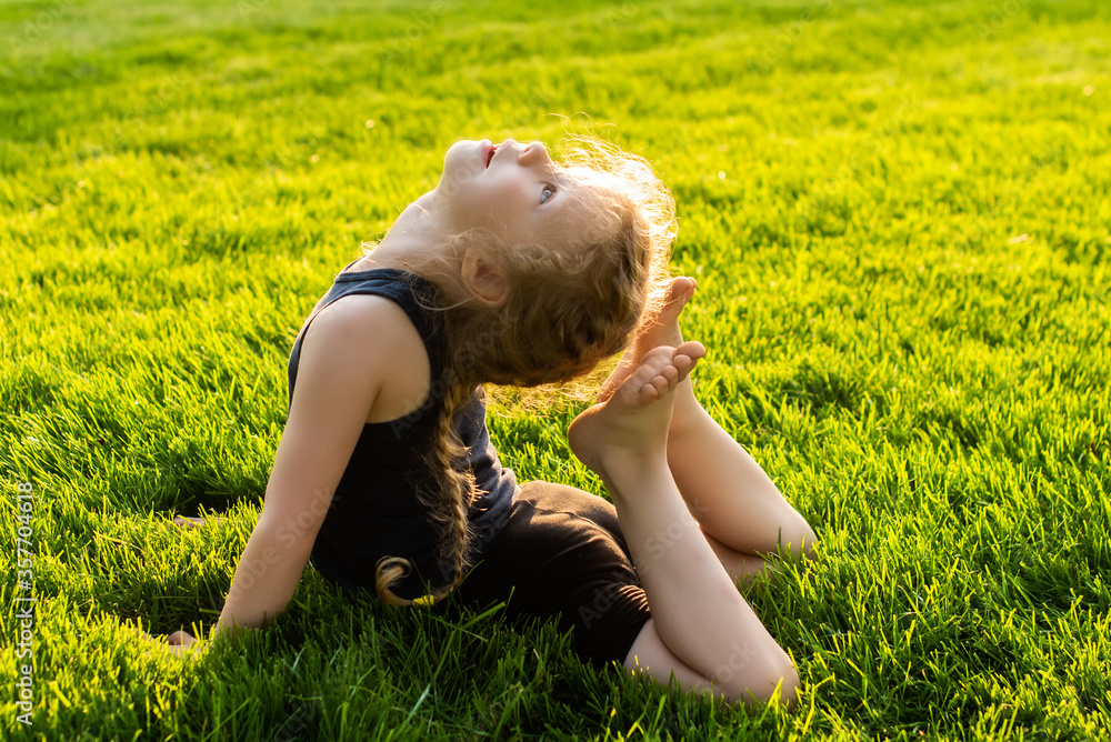 little girl with pigtails smiling do yoga in the park. stretching. child summer, sun, health. outdoor sports. healthy sport lifestyle. fitness, yoga little girl with pigtails smiling do yoga in the park. stretching. child summer, sun, health. outdoor sports. healthy sport lifestyle. fitness, yoga
