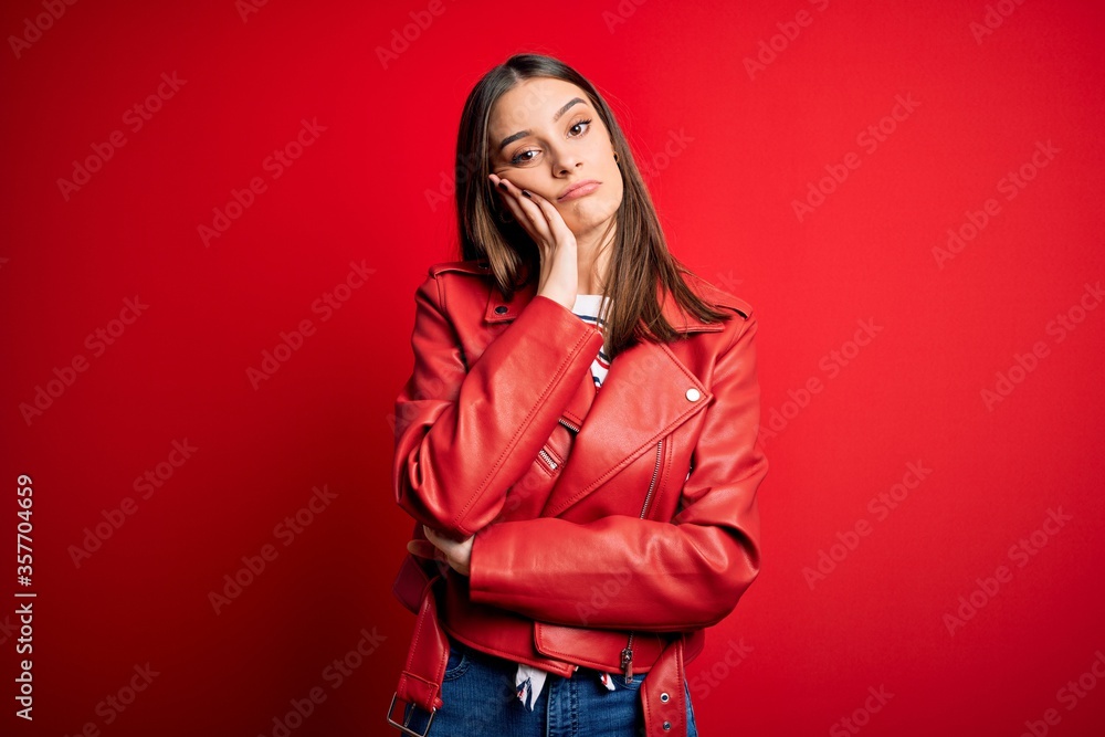 Young beautiful brunette woman wearing casual jacket standing over red background thinking looking tired and bored with depression problems with crossed arms. Young beautiful brunette woman wearing casual jacket standing over red background thinking looking tired and bored with depression problems with crossed arms.