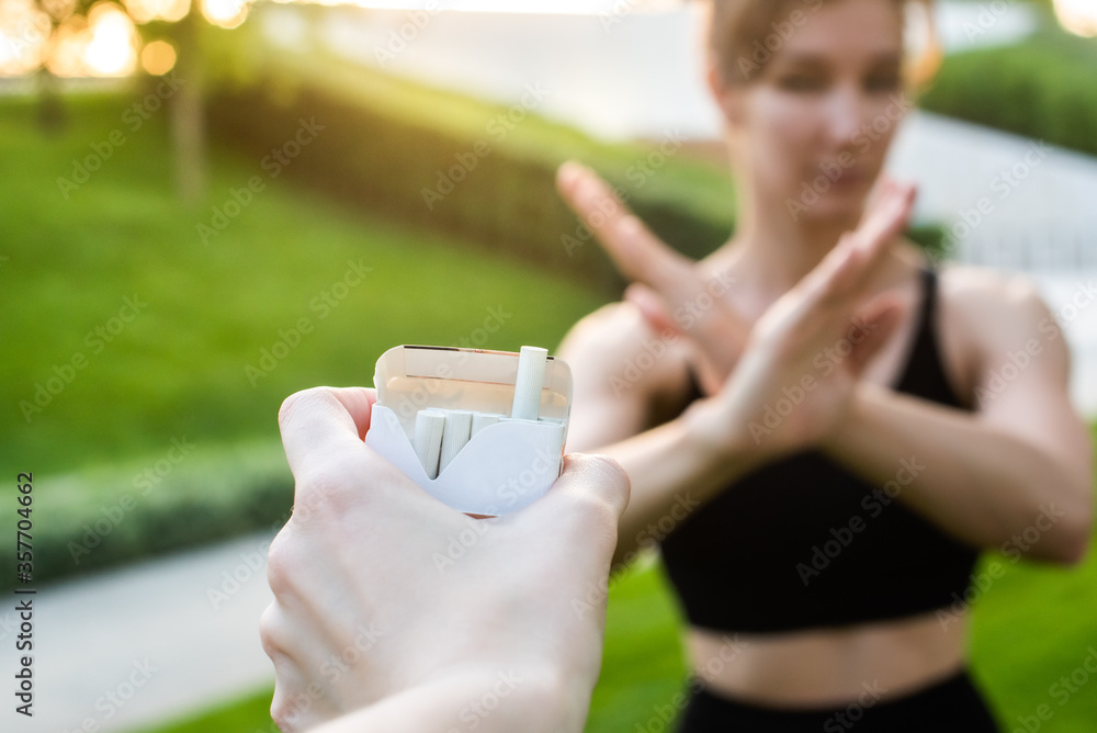 young woman refuses cigarettes. shows with hands a stop symbol. hand holds out her cigarettes. smoking cessation concept. healthy lifestyle young woman refuses cigarettes. shows with hands a stop symbol. hand holds out her cigarettes. smoking cessation concept. healthy lifestyle