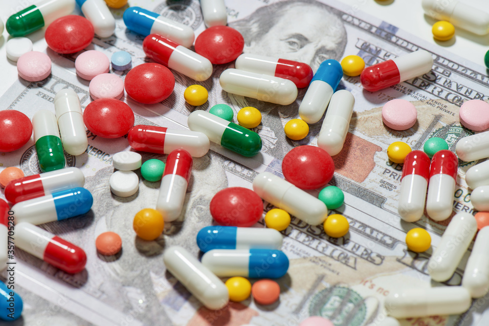 Different pills, capsules scattered over money, dollar background. Health care, expensive treatment concept Different pills, capsules scattered over money, dollar background. Health care, expensive treatment concept