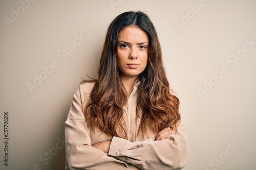 Young beautiful brunette woman wearing casual shirt standing over white background skeptic and nervous, disapproving expression on face with crossed arms. Negative person.