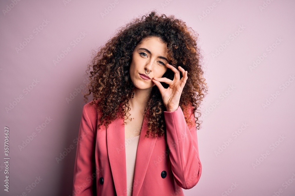 Young beautiful businesswoman with curly hair and piercing wearing elegant jacket mouth and lips shut as zip with fingers. Secret and silent, taboo talking Young beautiful businesswoman with curly hair and piercing wearing elegant jacket mouth and lips shut as zip with fingers. Secret and silent, taboo talking