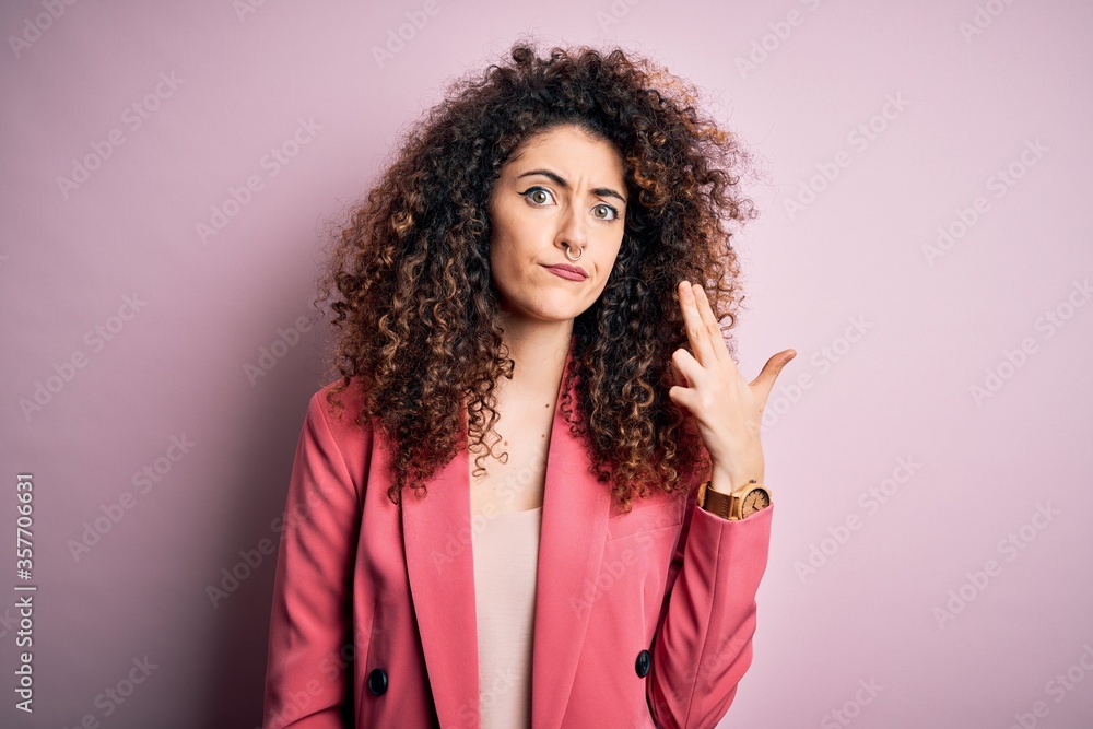 Young beautiful businesswoman with curly hair and piercing wearing elegant jacket Shooting and killing oneself pointing hand and fingers to head like gun, suicide gesture. Young beautiful businesswoman with curly hair and piercing wearing elegant jacket Shooting and killing oneself pointing hand and fingers to head like gun, suicide gesture.