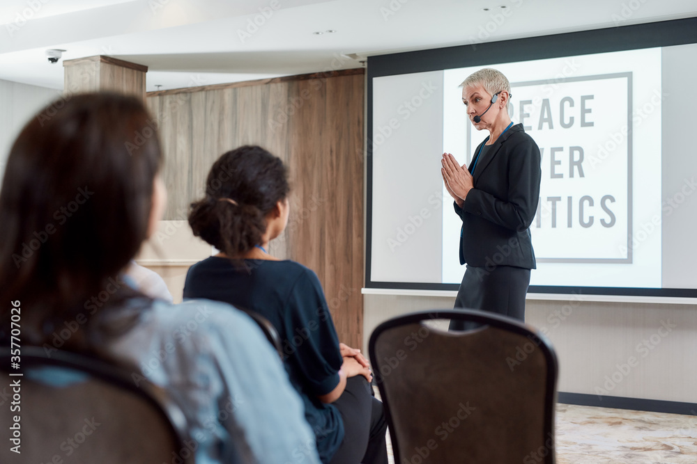 World of Opportunities. Female speaker in suit with headset giving a talk on Peace over Politics on corporate business meeting World of Opportunities. Female speaker in suit with headset giving a talk on Peace over Politics on corporate business meeting