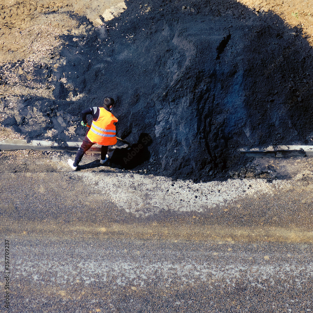 A road worker and a big pile of hot asphalt