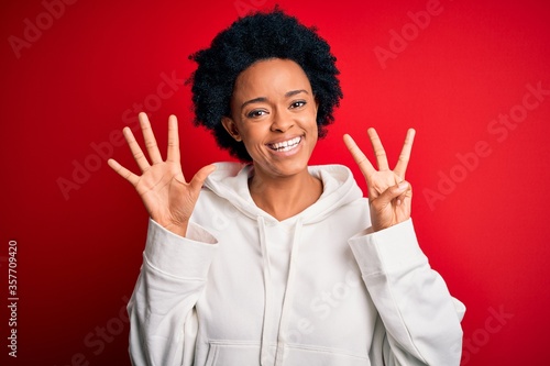 Young beautiful African American afro sportswoman with curly hair wearing sportswear showing and pointing up with fingers number eight while smiling confident and happy.
