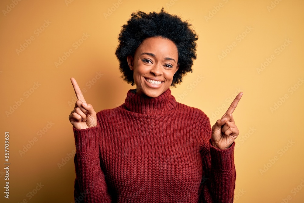 Young beautiful African American afro woman with curly hair wearing casual turtleneck sweater smiling confident pointing with fingers to different directions. Copy space for advertisement Young beautiful African American afro woman with curly hair wearing casual turtleneck sweater smiling confident pointing with fingers to different directions. Copy space for advertisement