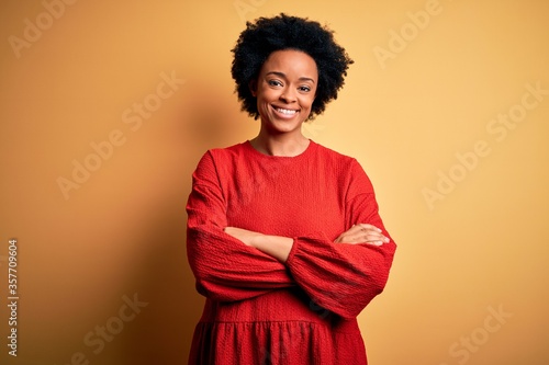 Young beautiful African American afro woman with curly hair wearing casual sweater happy face smiling with crossed arms looking at the camera. Positive person.
