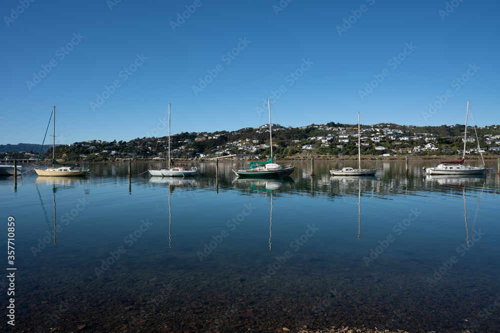 View of yachts and boats reflecting in the water docked in Porirua near Wellington New Zealand on a calm sunny day