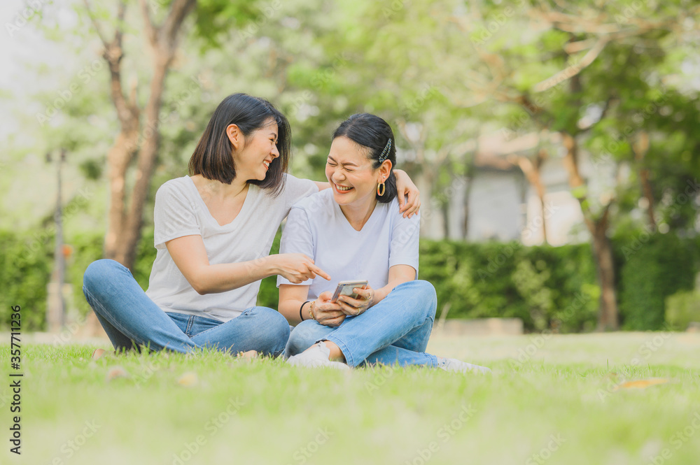 Asian women laughing while using smartphone outdoor Asian women laughing while using smartphone outdoor