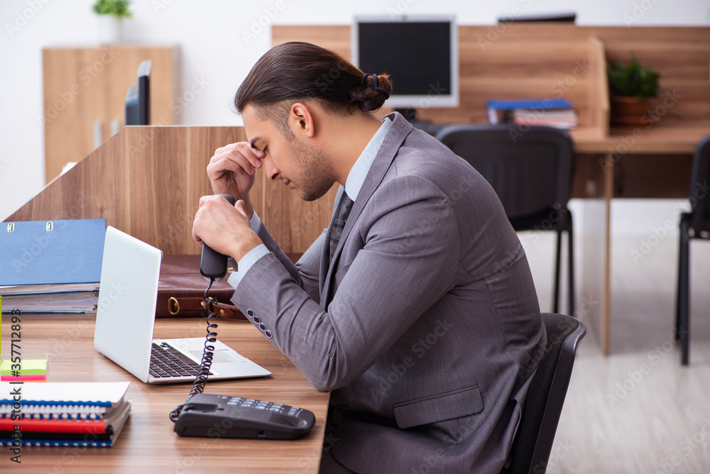 Young male employee unhappy with excessive work Young male employee unhappy with excessive work