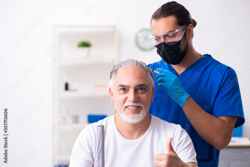 Obraz premium Old man visiting young male doctor in hair transplantation conce