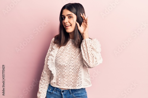 Young beautiful girl wearing casual t shirt smiling with hand over ear listening and hearing to rumor or gossip. deafness concept. © Krakenimages.com