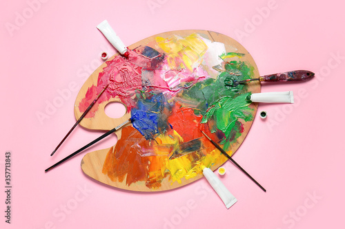 Artist's palette with paints on color background