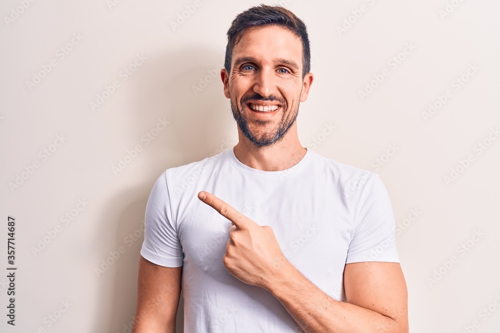 Young handsome man wearing casual t-shirt standing over isolated white background smiling cheerful pointing with hand and finger up to the side Young handsome man wearing casual t-shirt standing over isolated white background smiling cheerful pointing with hand and finger up to the side