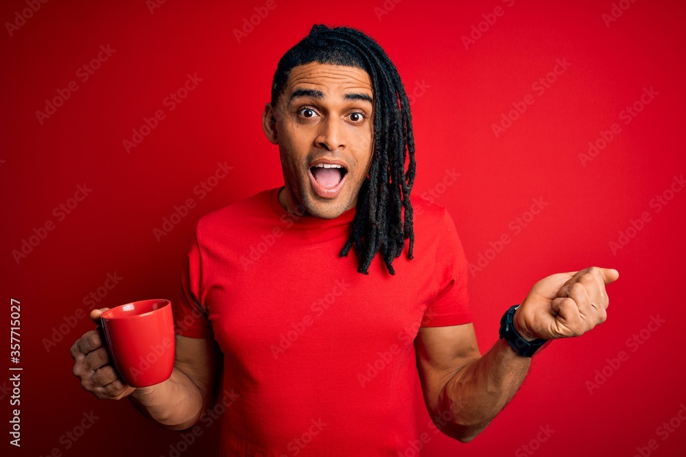 Young african american afro man drinking cup of coffe over red background screaming proud and celebrating victory and success very excited, cheering emotion Young african american afro man drinking cup of coffe over red background screaming proud and celebrating victory and success very excited, cheering emotion