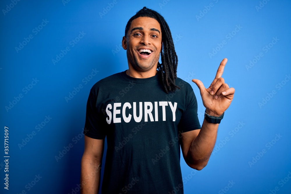 Young african american afro safeguard man with dreadlocks wearing security uniform surprised with an idea or question pointing finger with happy face, number one Young african american afro safeguard man with dreadlocks wearing security uniform surprised with an idea or question pointing finger with happy face, number one