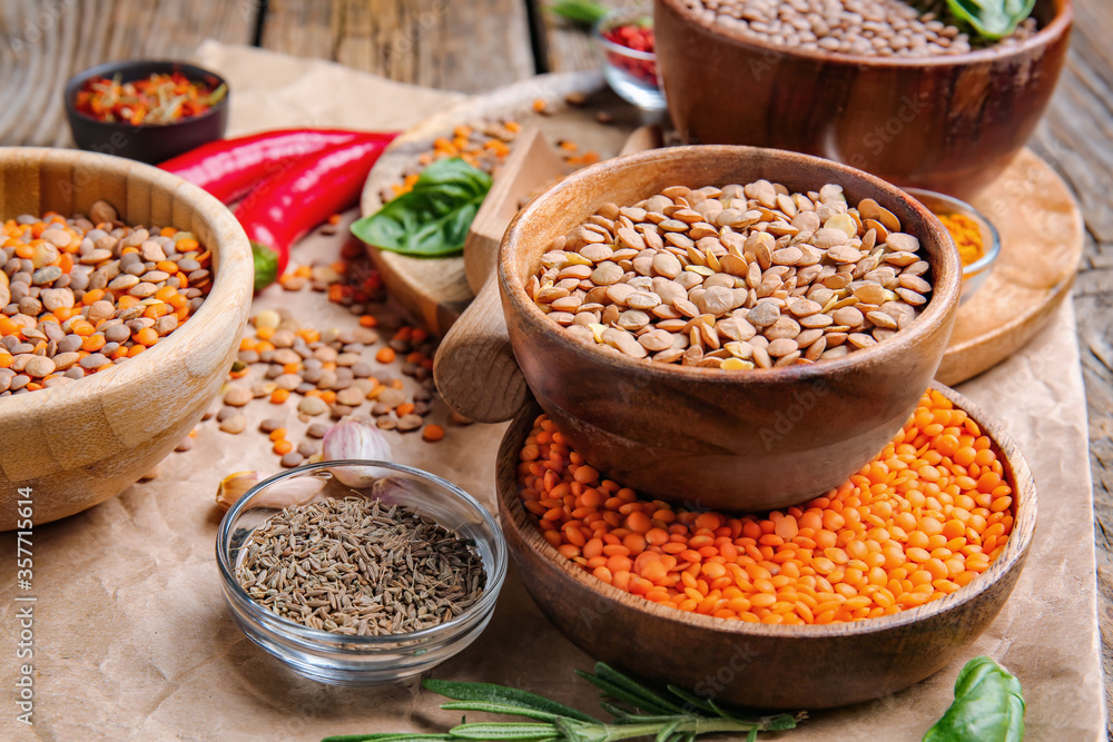 Different raw lentils with spices on table