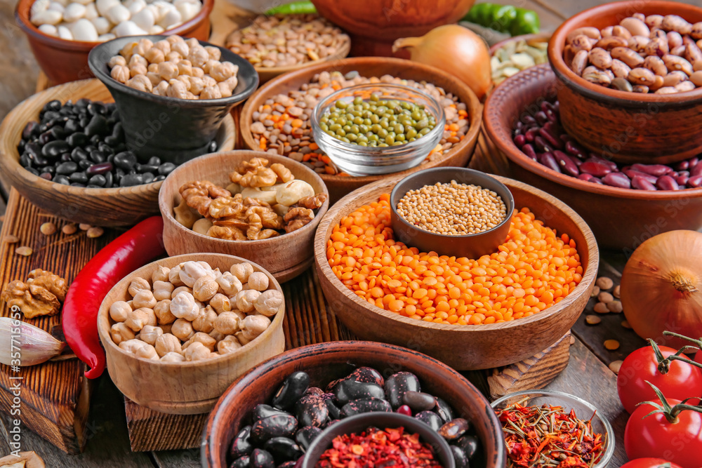 Different raw legumes with spices on table