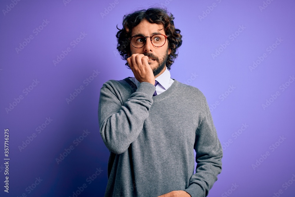 Handsome businessman with beard wearing tie and glasses standing over purple background looking stressed and nervous with hands on mouth biting nails. Anxiety problem. Handsome businessman with beard wearing tie and glasses standing over purple background looking stressed and nervous with hands on mouth biting nails. Anxiety problem.