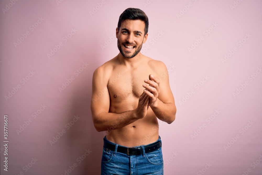 Young handsome strong man with beard shirtless standing over isolated pink background clapping and applauding happy and joyful, smiling proud hands together