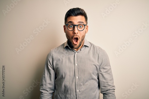 Young handsome man wearing elegant shirt and glasses over isolated white background afraid and shocked with surprise expression, fear and excited face. © Krakenimages.com